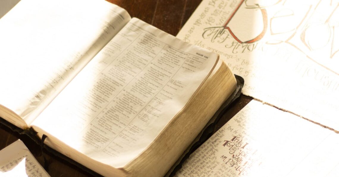 Open Bible with hand-drawn illustrations on a rustic wooden table, bathed in warm light.
