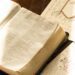 Open Bible with hand-drawn illustrations on a rustic wooden table, bathed in warm light.
